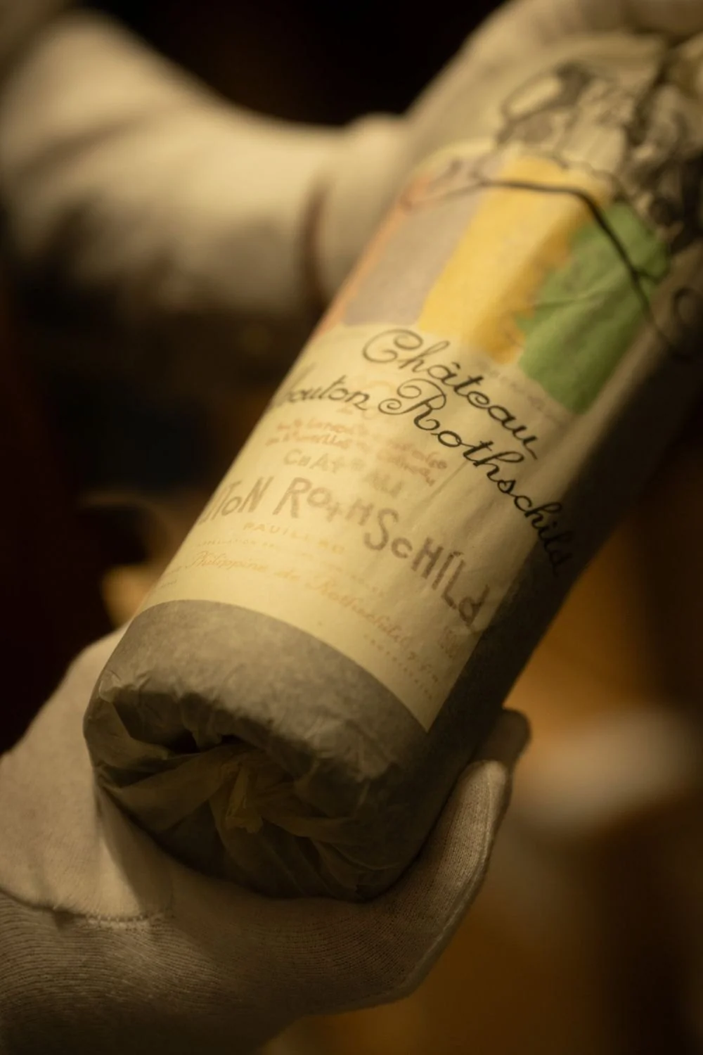 Behandschuhte Hand hält eine Flasche Château Mouton Rothschild